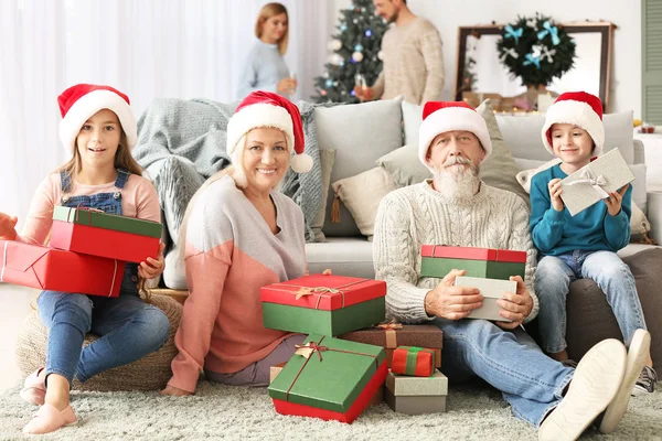 Happy grandparents and little children with Christmas gifts at home