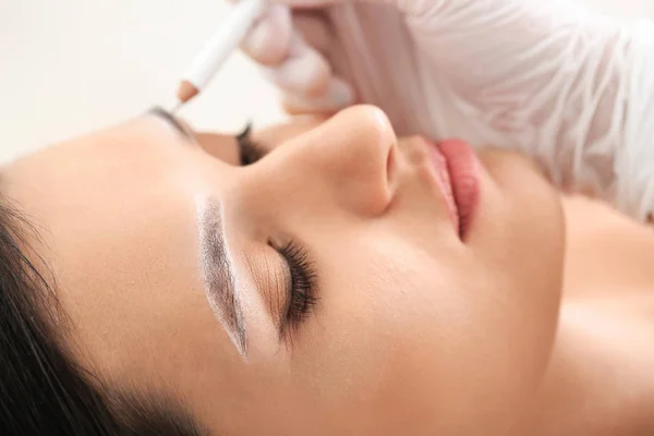 Young woman undergoing eyebrow correction procedure in beauty salon, closeup — Stock Photo, Image