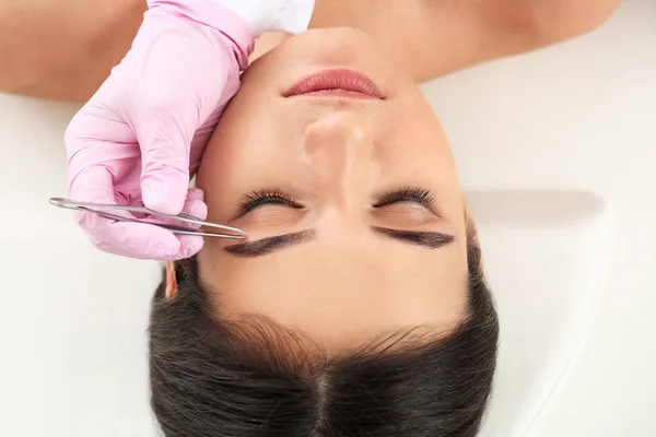 Young woman undergoing eyebrow correction procedure in beauty salon — Stock Photo, Image