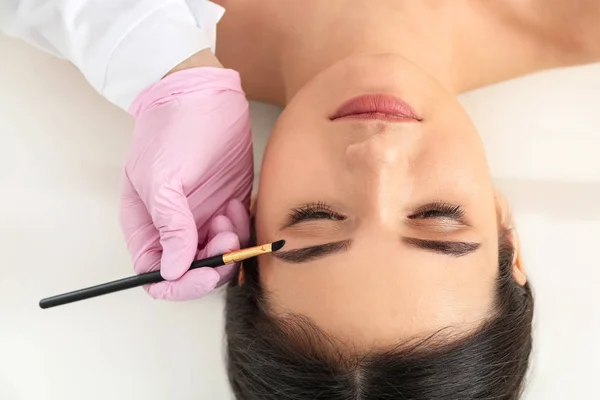 Young woman undergoing eyebrow correction procedure in beauty salon — Stock Photo, Image