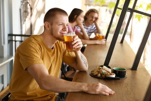 Young man drinking fresh beer in pub — Stock Photo, Image