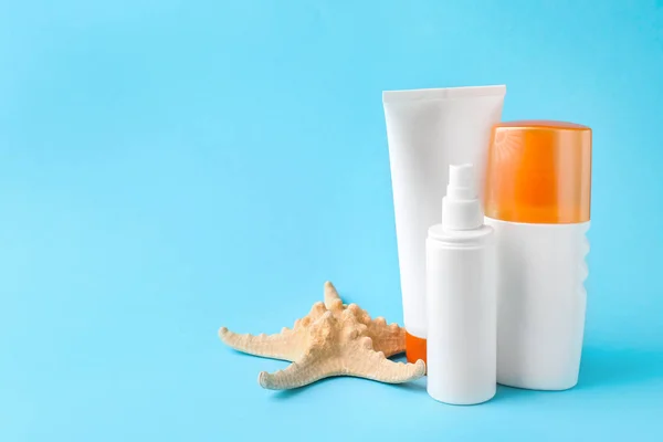 Different sun protection creams and starfish on color background — Stock Photo, Image