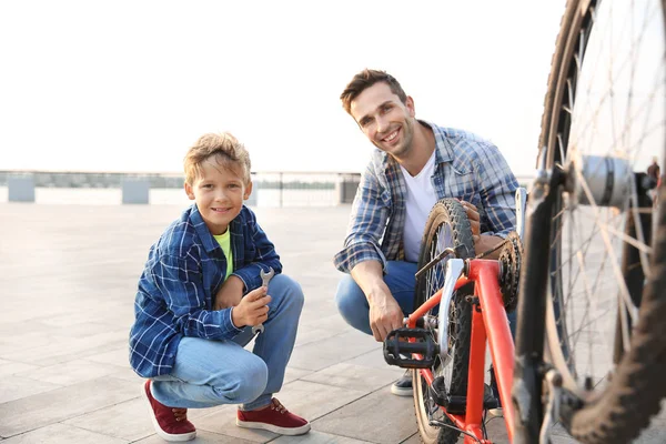 Pai e seu filho reparando bicicleta ao ar livre — Fotografia de Stock