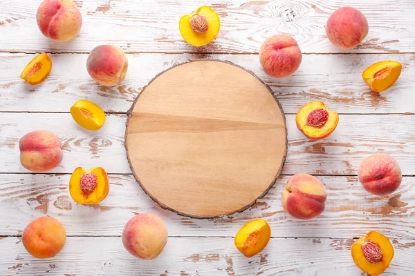 Стиглі персики і дошка на білому дерев'яному фоні — стокове фото