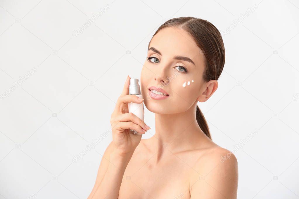 Woman applying serum onto her face against white background