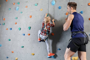 Eğitmen spor salonunda duvara tırmanmak için küçük kız öğretim