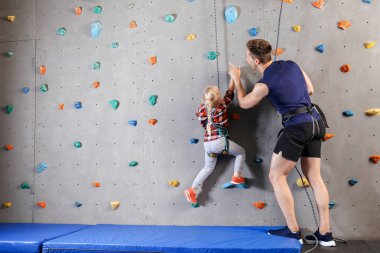 Eğitmen spor salonunda duvara tırmanmak için küçük kız öğretim