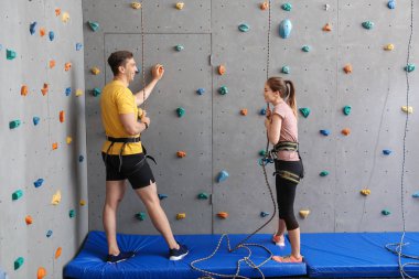 Spor salonunda duvar tırmanma eğitmeni ile genç adam