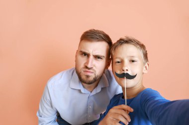 Baba ve küçük oğlu renkli arka planda komik selfie alıyor