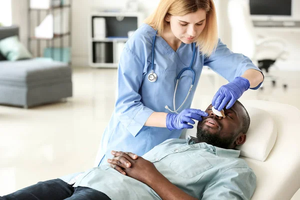 Plastic surgeon examining African-American man after operation in clinic — Stock Photo, Image