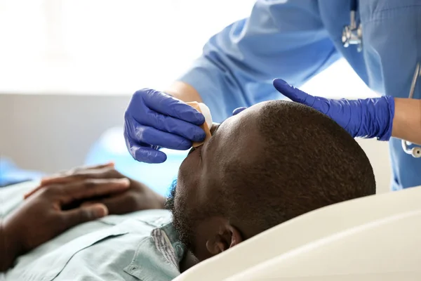 Plastikkirurg undersöker afro-amerikansk man efter operation i kliniken — Stockfoto