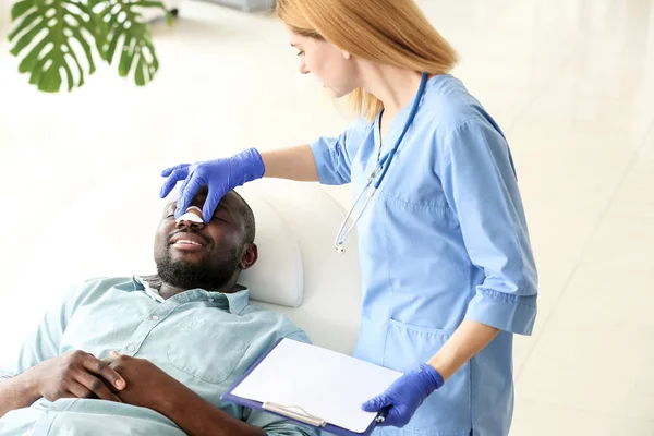 Plastic surgeon examining African-American man after operation in clinic — Stock Photo, Image