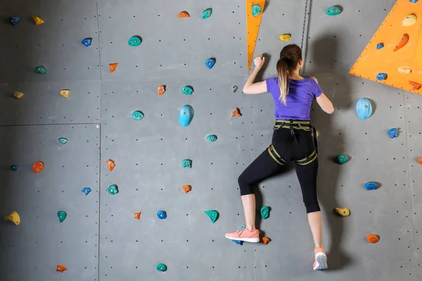 Jovem mulher escalada parede no ginásio — Fotografia de Stock