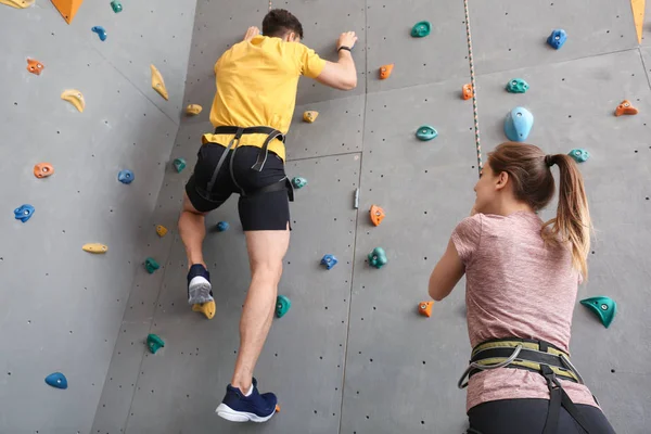 Young man with instructor climbing wall in gym — Stock Photo, Image