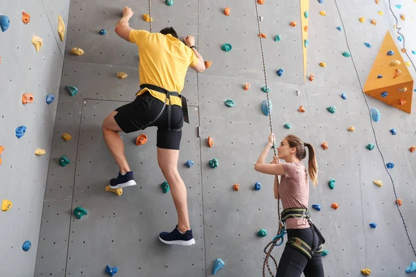 Joven con instructor escalando pared en el gimnasio — Foto de Stock