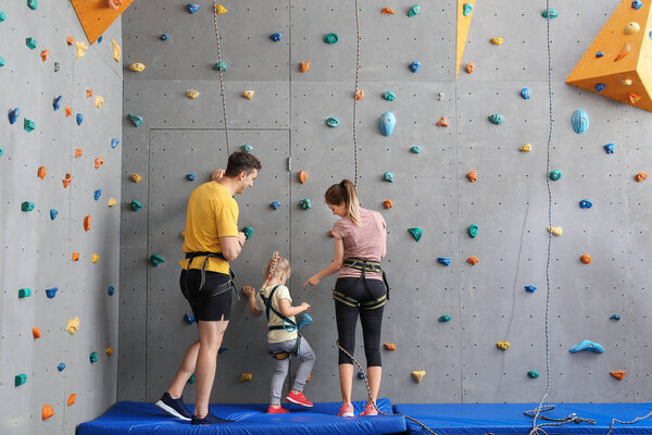 Little girl with parents in climbing gym