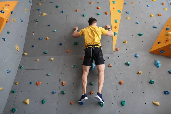 Young man climbing wall in gym — Stock Photo, Image