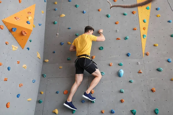 Молодой человек карабкается по стене в спортзале — стоковое фото