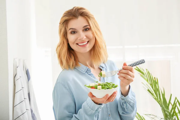 Женщина с овощным салатом на кухне — стоковое фото