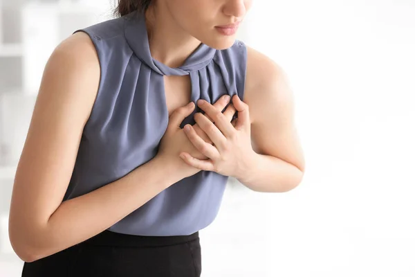 Young woman suffering from heart attack in office — Stock Photo, Image