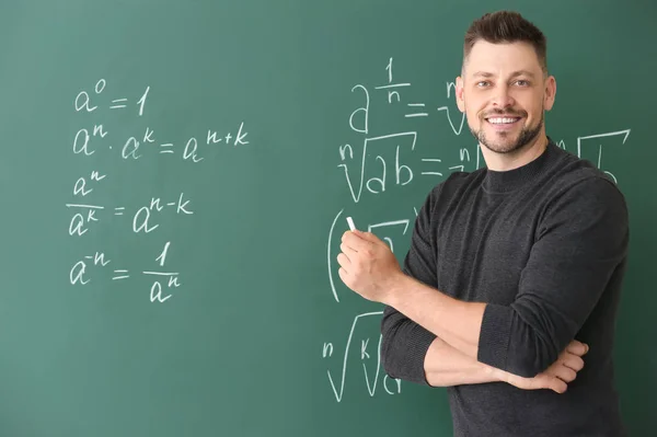 Guapo profesor de matemáticas escribiendo en pizarra en el aula — Foto de Stock