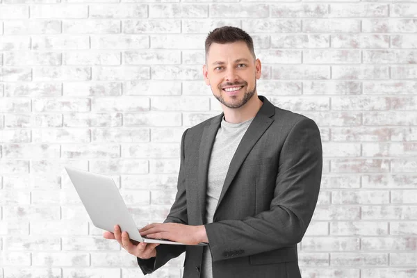 Bonito professor masculino com laptop perto da parede de tijolo — Fotografia de Stock