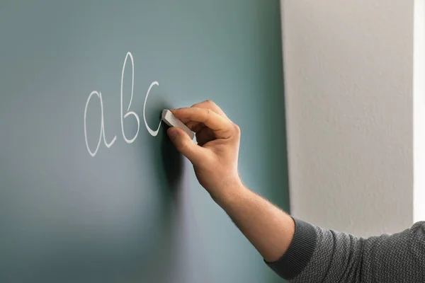 Male teacher writing on blackboard in classroom — Stock Photo, Image