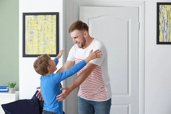 Happy little boy meeting his father at home