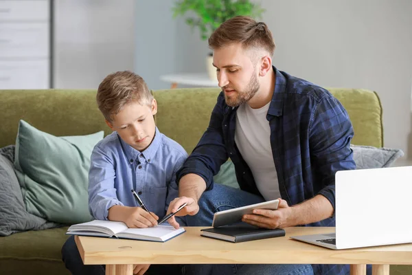 Ο πατέρας βοηθάει το γιο του να κάνει μαθήματα στο σπίτι. — Φωτογραφία Αρχείου