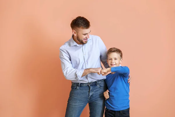 Apa és a kisfia bumping ököllel ellen színes háttér — Stock Fotó