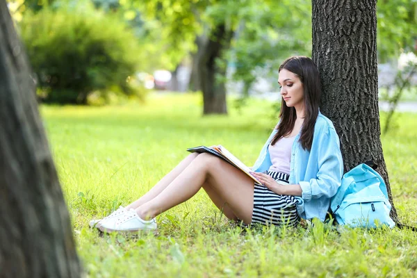Belle étudiante assise sous un arbre dans le parc — Photo