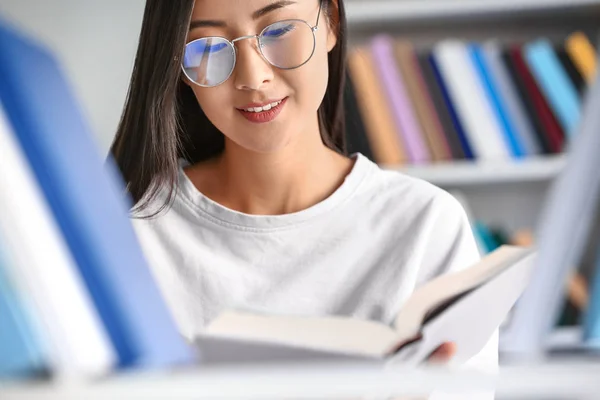 Joven estudiante asiático eligiendo libros en la biblioteca —  Fotos de Stock