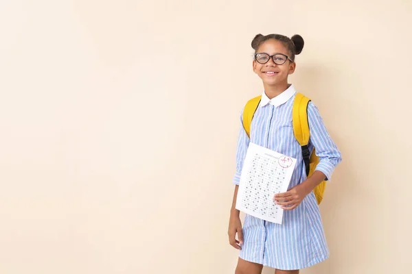 Felice ragazza afro-americana con i risultati del test scolastico su sfondo chiaro — Foto Stock