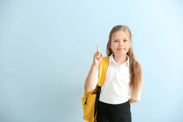 Little schoolgirl with raised index finger on color background — Stock Photo, Image