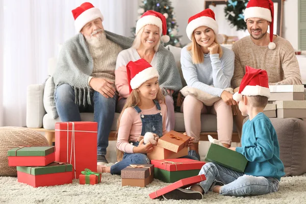 Niños pequeños con su familia abriendo regalos de Navidad en casa —  Fotos de Stock