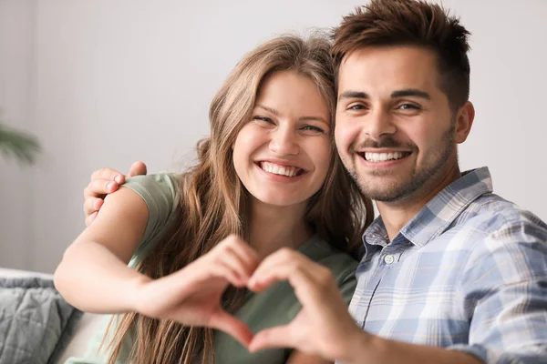 Retrato de casal amoroso feliz de mãos dadas em forma de coração em casa — Fotografia de Stock