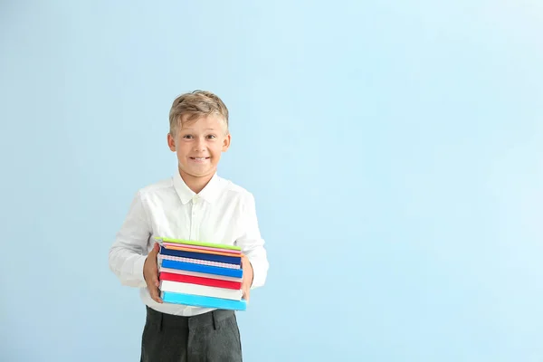 Little schoolboy with books on color background — Stock Photo, Image