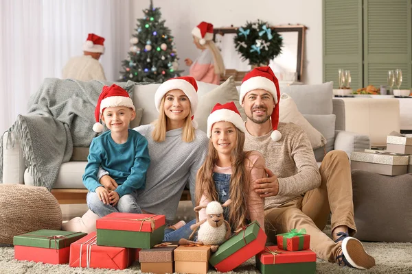 Familia feliz con cajas de regalo en la habitación decorada para Navidad — Foto de Stock