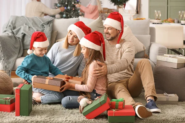 Familia feliz con cajas de regalo en la habitación decorada para Navidad — Foto de Stock