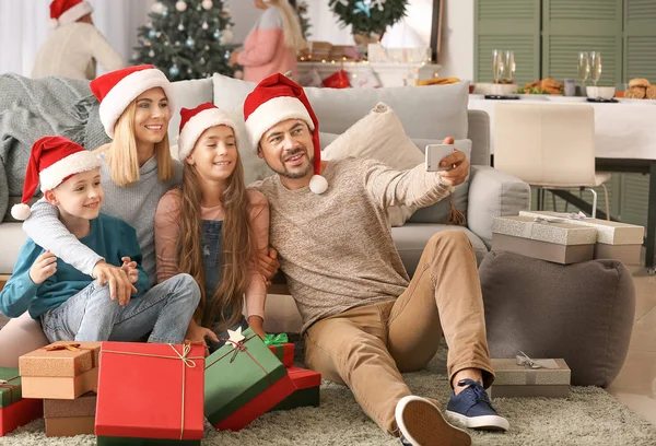 Família feliz com presentes de Natal levando selfie em casa — Fotografia de Stock