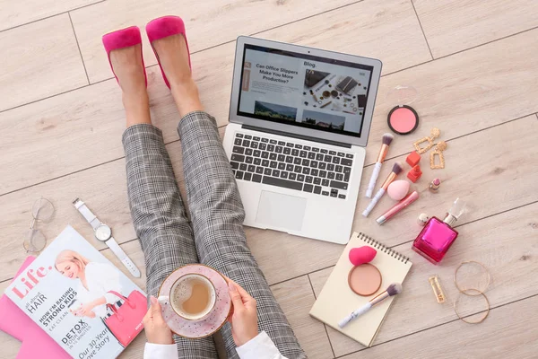 Female beauty blogger with laptop and cup of coffee sitting on wooden floor, top view — Stock Photo, Image