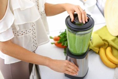 Genç kadın mutfakta sağlıklı smoothie hazırlanıyor