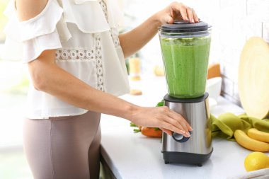 Genç kadın mutfakta sağlıklı smoothie hazırlanıyor