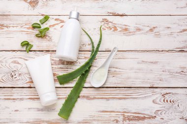 Beyaz ahşap arka plan üzerinde aloe yaprakları ile doğal krem
