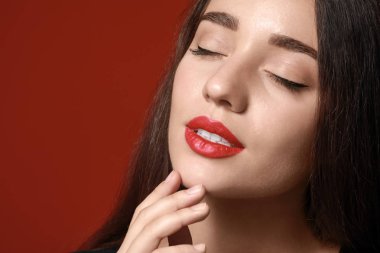 Renk arka planında parlak ruj olan güzel genç bir kadın.