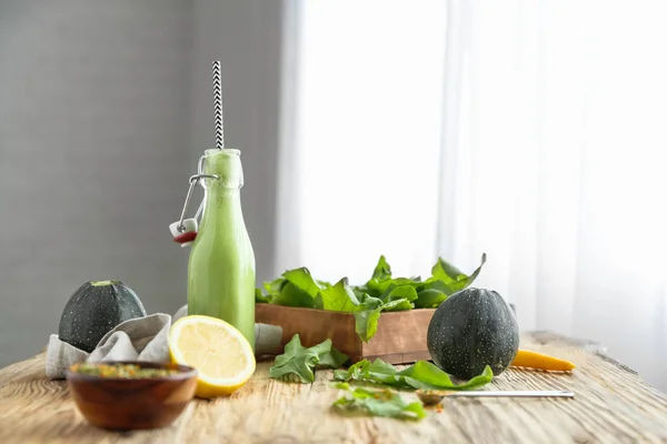 Bottle of tasty smoothie with ingredients on table in kitchen — Stock Photo, Image