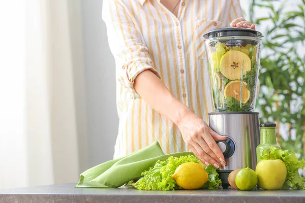 Mujer joven preparando batido saludable en la cocina — Foto de Stock