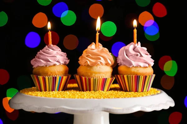 Sabrosos cupcakes de cumpleaños en stand contra luces desenfocadas — Foto de Stock