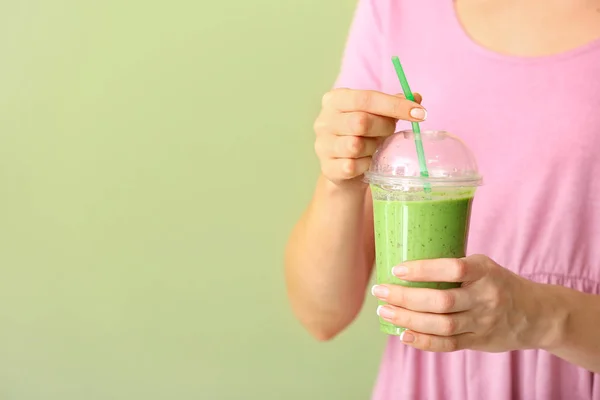 Young woman with cup of tasty green smoothie on color background — Stock Photo, Image