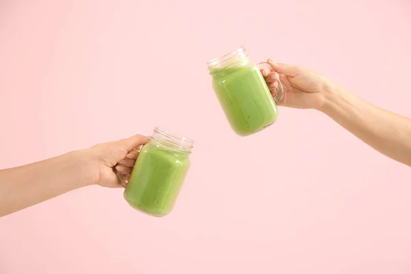 Female hands with tasty green smoothie in mason jars on color background — Stock Photo, Image